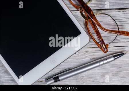 Digitale Tablet auf einem Holztisch mit Brillen und Kugelschreiber Stockfoto