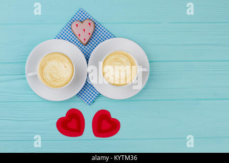 Weiße Tassen Cappuccino und roten Herzen. Zwei Porzellantassen mit Kaffee trinken, handgefertigte Herzen und herzförmige Plätzchen. Valentines Tag Kaffee gesundes Stockfoto