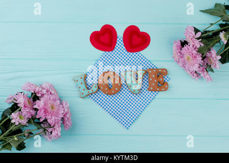 Rote Herzen und Cookies für Valentines Tag. Wort der Liebe von gebackenen Plätzchen und Papier Herz, blau Holz- Hintergrund. Zusammensetzung mit Blumen für Valenti Stockfoto