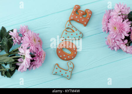 Valentines Tag Holz- gruss Hintergrund. Wort Liebe aus Blau und Braun cookies und frische Blumen, blau Holz- Hintergrund. Schönen Valentines Tag c Stockfoto