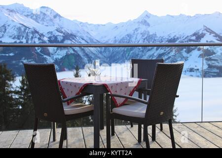 Stühle auf der Terrasse des Cafés in die Berge und die Aussicht auf die Hohen Tauern in der Region Zell am See - Kaprun, im Winter. Österreich, Europa. Stockfoto