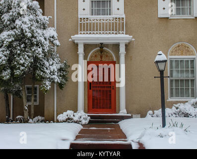 Eingang des eleganten upscale Stuck Haus mit Säulen und Fliesen im Schnee mit leuchtend roten Tür und schaufelte Bürgersteig Stockfoto