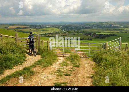 Eine männliche Radfahrer auf dem Mountainbike zu einem Tor auf der South Downs Way Wanderweg in der Nähe von Lewes, East Sussex. Stockfoto