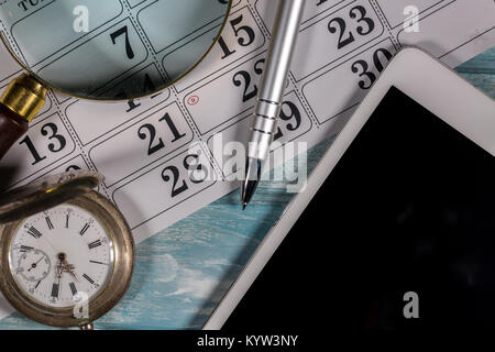 Lupe, silber Taschenuhr, Digitale Tablet Computer, Kalender und Kugelschreiber sind auf einem Holztisch Hintergrund platziert Stockfoto