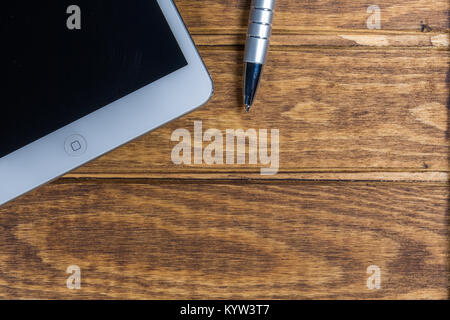 Digitale Tablet Computer und Kugelschreiber sind auf einem Holztisch Hintergrund platziert Stockfoto