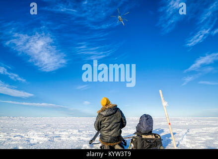 Landung eines Hubschraubers auf einer Eisscholle in der Arktis. Ein Mann wartet auf einen Hubschrauber Stockfoto