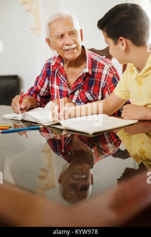 Kleiner Junge macht Schule Hausaufgaben mit alten Menschen zu Hause. Stockfoto