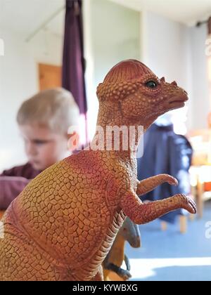 Nahaufnahme von Spielzeug Dinosaurier mit Kind im Hintergrund Stockfoto