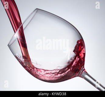 Rotwein in Glas mit grauem Hintergrund weiß Gießen Stockfoto