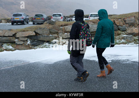 Llanberis, Gwynedd, Wales, UK. 16 Jan, 2018. Ein junges Paar mutigen Ein plötzlicher Hagel die Hits Llanberis Pass, in der Nähe von Llanberis, Gwynedd, Wales, UK. Credit: Graham M. Lawrence/Alamy leben Nachrichten Stockfoto