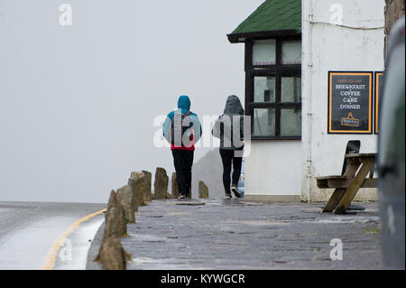 Llanberis, Gwynedd, Wales, UK. 16 Jan, 2018. Ein junges Paar zu Fuß in der Nähe der Jugendherberge wie Blizzards von Schnee und Hagel mit Gale force Winds hit Pen-Y-Pass, in der Nähe von Llanberis, Gwynedd, Wales, UK. Credit: Graham M. Lawrence/Alamy leben Nachrichten Stockfoto