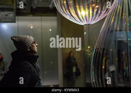 London, Großbritannien. 16 Jan, 2018. Präsentieren Künstler aus aller Welt, mit Schwerpunkt auf modernste Technologie, Winter Lights erfolgt in Canary Wharf. Holons durch Michiel Martens und Jetske Visser in Crossrail Ort Mann reflektiert betrachtet die Installation. Quelle: Carol Moir/Alamy Leben Nachrichten. Stockfoto