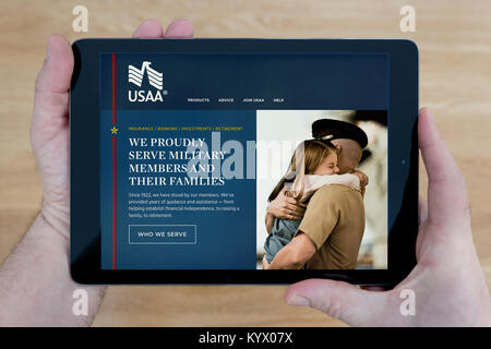 Ein Mann schaut auf die United Services Automobile Association (Usaa) Website auf seinem iPad Tablet, mit einem hölzernen Tischplatte Hintergrund (nur redaktionell) Stockfoto