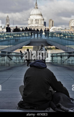 Ein junger Obdachloser wartet mit seinem Hund am Ende der Millenium Bridge, vor der St. Pauls Kathedrale in London. Stockfoto