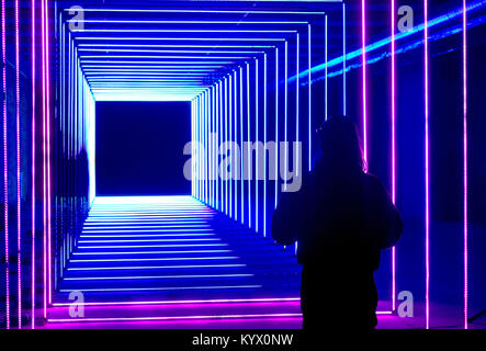 Eine Frau steht vor auf Ihrer Wellenlänge, eine Installation an der Canary Wharf Winter Lights Festival präsentiert, wie Skulpturen, Bauten und Anlagen sind in verschiedenen Formen des Lichts Technologie vorgestellt. Stockfoto