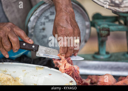 Otavalo, Ecuador - 30. Dezember 2017: Nahaufnahme von Hand schneiden Metzger Fleisch mit Messer in der wöchentliche Bauernmarkt Stockfoto
