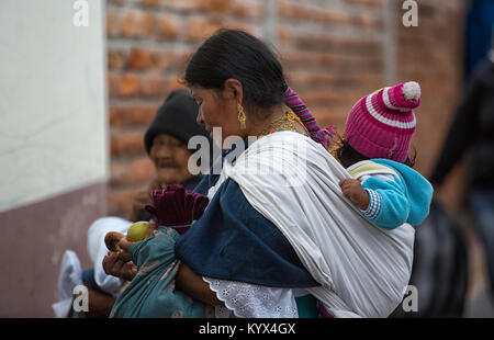 Otavalo, Ecuador - 30. Dezember 2017: indigenen Quechua Frau mit Kind auf dem Rücken auf dem lokalen Markt Stockfoto