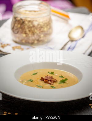 Rote Linsensuppe mit gegrillten Würstchen in Weiß Platte auf dunklem Stein Stockfoto