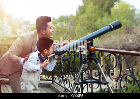 Der Vater und der Sohn verwendet ein astronomisches Teleskop auf der Terrasse Stockfoto