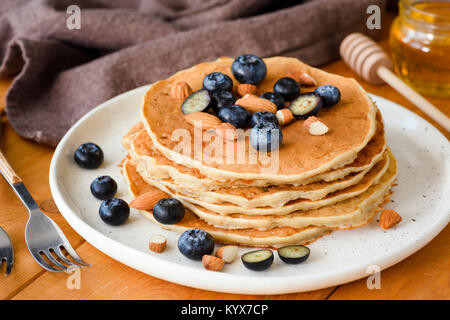 Pfannkuchen mit Heidelbeeren, Honig und Mandeln auf weiße Platte. Detailansicht, selektiver Fokus Stockfoto