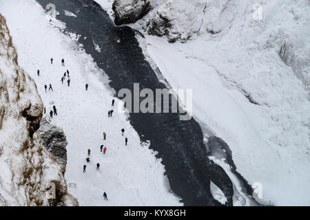 Der 62 Meter hohe Wasserfall Skogafoss im südlichen Island als Menschen bewundern die Teil eingefroren fällt. Stockfoto