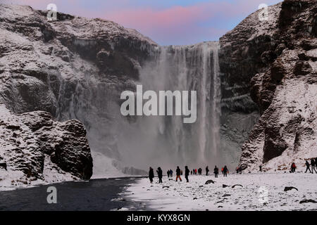 Der 62 Meter hohe Wasserfall Skogafoss im südlichen Island als Menschen bewundern die Teil eingefroren fällt. Stockfoto