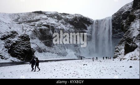 Der 62 Meter hohe Wasserfall Skogafoss im südlichen Island als Menschen bewundern die Teil eingefroren fällt. Stockfoto