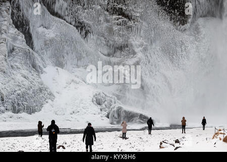 Der 62 Meter hohe Wasserfall Skogafoss im südlichen Island als Menschen bewundern die Teil eingefroren fällt. Stockfoto