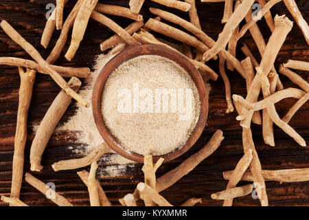 Ashwagandha Wurzeln und Pulver in Houten auf hölzernen Tisch von oben. Flach. Top Shot. Stockfoto