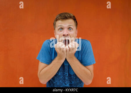 In dem Bestreben, Mann ist schockiert und seinen Mund öffnen in der Überraschung auf rotem Hintergrund Stockfoto