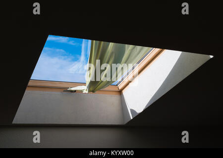 In der letzten Etage Fenster, den blauen Himmel hinter dem grünen Vorhang gesehen werden. Dachfenster Stockfoto