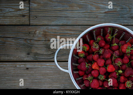 Hohe Betrachtungswinkel von Erdbeeren in Sieb auf hölzernen Tisch Stockfoto