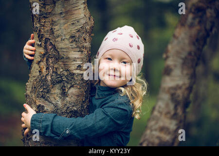 Portrait von süße Mädchen umarmt Baum im Park Stockfoto