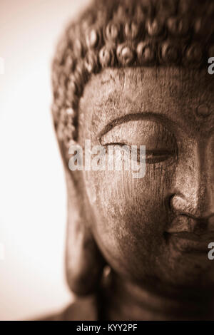 Dies ist eine Nahaufnahme eines antiken Holz schnitzen einer Skulptur von Buddha mit Fokus auf die niedergeschlagenen Augen. Das Bild wurde mit einem Lensbaby genommen Stockfoto