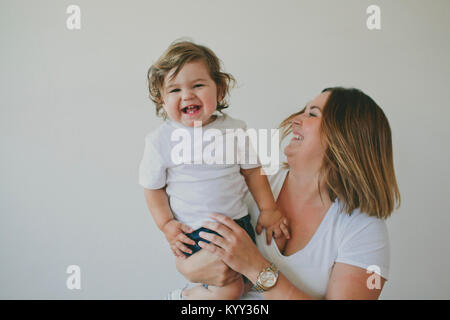 Portrait von fröhlichen Sohn von Mutter gegen die Wand zu Hause durchgeführt werden Stockfoto