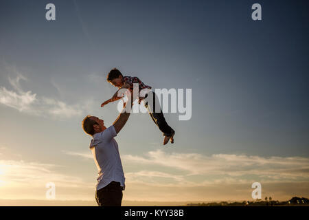 Low Angle View von Vater, Sohn in Luft am Strand gegen Sky Stockfoto