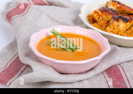 Ansicht der Linsensuppe serviert in rosa Schüssel mit Rosmarin und Bulgur Pilaw aus Zweikorn mit gegrilltem Huhn, auf Stoff Hintergrund. Stockfoto