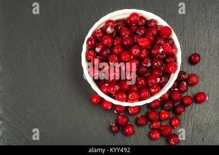 Gefrorene Beeren der Cranberries in Weiß Schüssel auf schwarzem Stein. Studio Foto Stockfoto