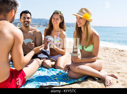 Vier lächelnd nach Freunden Karten auf Sand Sommer Strand. Selektiver Fokus Stockfoto