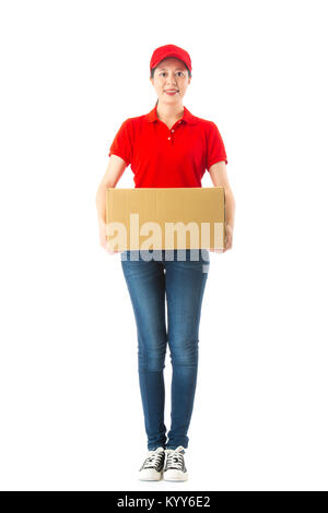 Volle Länge Foto von professionellen Junge weibliche Delivery officer Holding Big Box, die in weiße Wand im Hintergrund und das Gesicht zur Kamera. Stockfoto