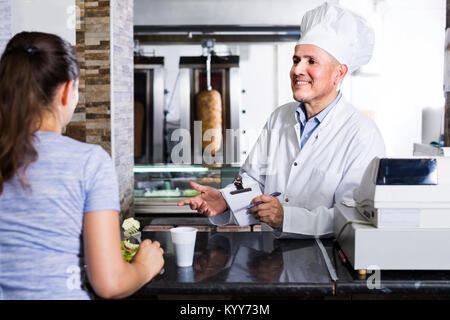 Latino Mann Koch in Uniform, Auftrag vom Kunden in fast food Restaurant Stockfoto