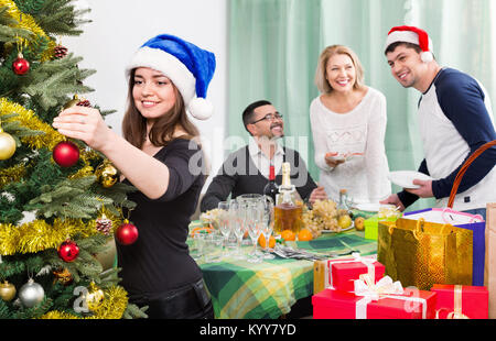 Glücklich lächelnde Familie Einstellung Tisch für das Abendessen und Dekorieren Weihnachtsbaum Stockfoto