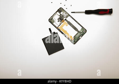Studio shot high-angle View close-up von Präzisions Schraubendreher und zerlegt Mobiltelefon mit Akku in ein Konzept der Austausch, Reparatur ein Stockfoto
