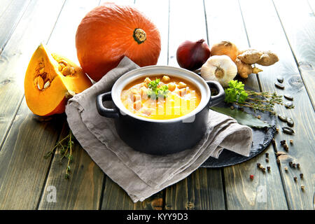 Pikante Kürbis creme Suppe mit Ingwer, Zwiebeln, Knoblauch und Chili in Keramik Schüssel auf den Holztisch. Die Suppe mit Croutons, Kürbiskerne serviert und Stockfoto