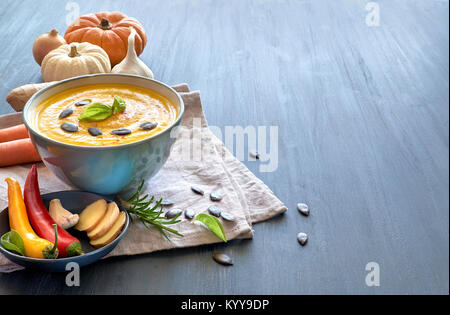 Würzige Kürbissuppe mit Möhren, Chili, Ingwer und Knoblauch, serviert mit Basi und Kürbiskernen. Holz- Hintergrund, Text Raum Stockfoto