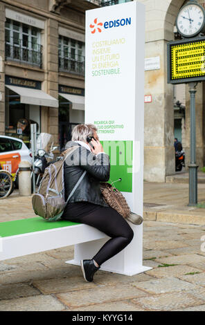 Frau mit einem Mobiltelefon an einem Edison Ladestation, in der Nähe der Theater La Scala, Mailand, Italien Stockfoto