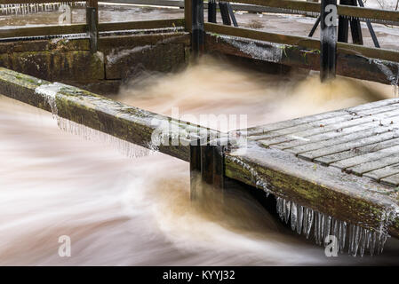 Eis und Eiszapfen bilden auf Balken und Geländer entlang einer gewalttätigen River. Stockfoto