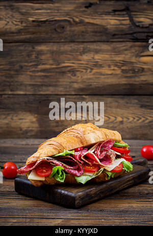 Leckeres Frühstück. Appetitlich Croissant mit Salami und Käse und Tomaten Stockfoto