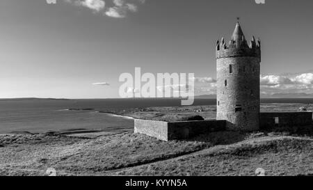 Doonagor Schloss in Irland, die mit Blick auf das Dorf Doolin am Fuß der Klippen von Moher. Die Aran Inseln können Sie in der Ferne gesehen werden. Stockfoto