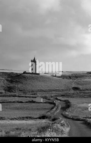 Doonagor Schloss in Irland, die mit Blick auf das Dorf Doolin am Fuß der Klippen von Moher. Die Aran Inseln können Sie in der Ferne gesehen werden. Stockfoto